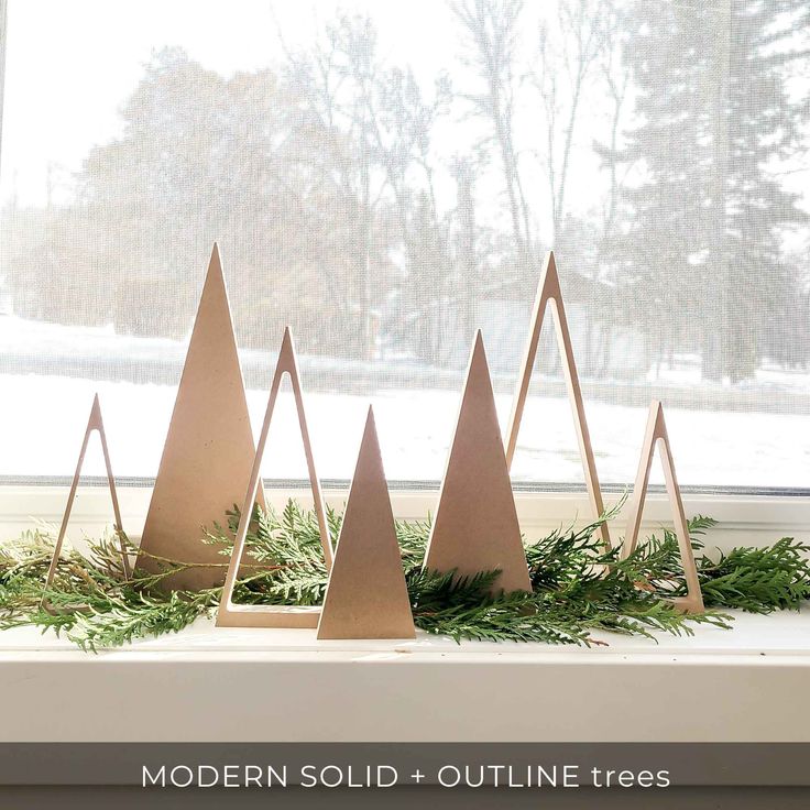 modern solid - outline trees are displayed in front of a window with snow on the ground