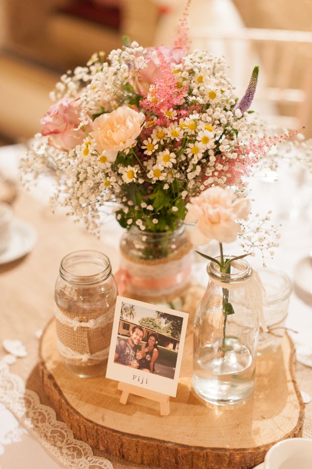 there is a vase with flowers in it on top of a wooden slice that has an old photo