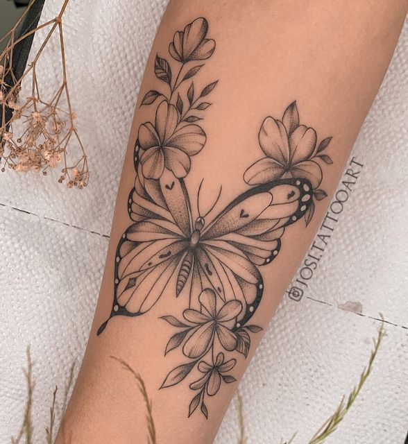 a woman's arm with a butterfly and flowers tattoo design on the left forearm