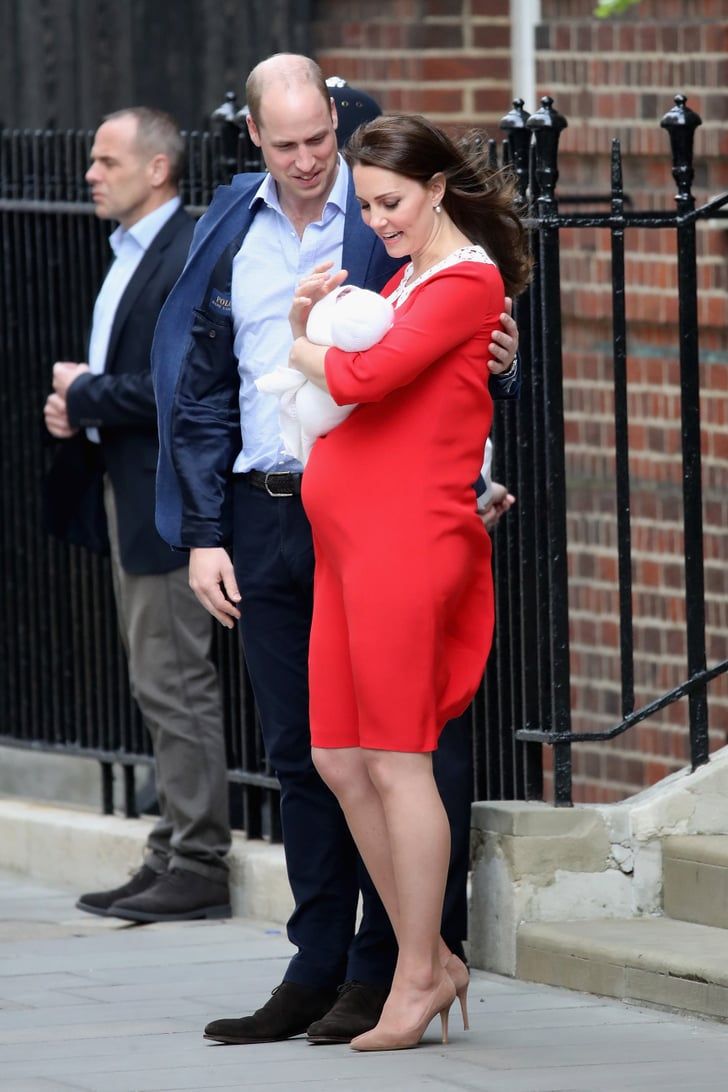 a woman in a red dress is hugging a man on the street while another man stands behind her