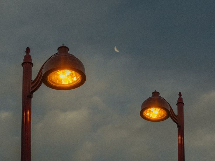 two street lights with the moon in the background