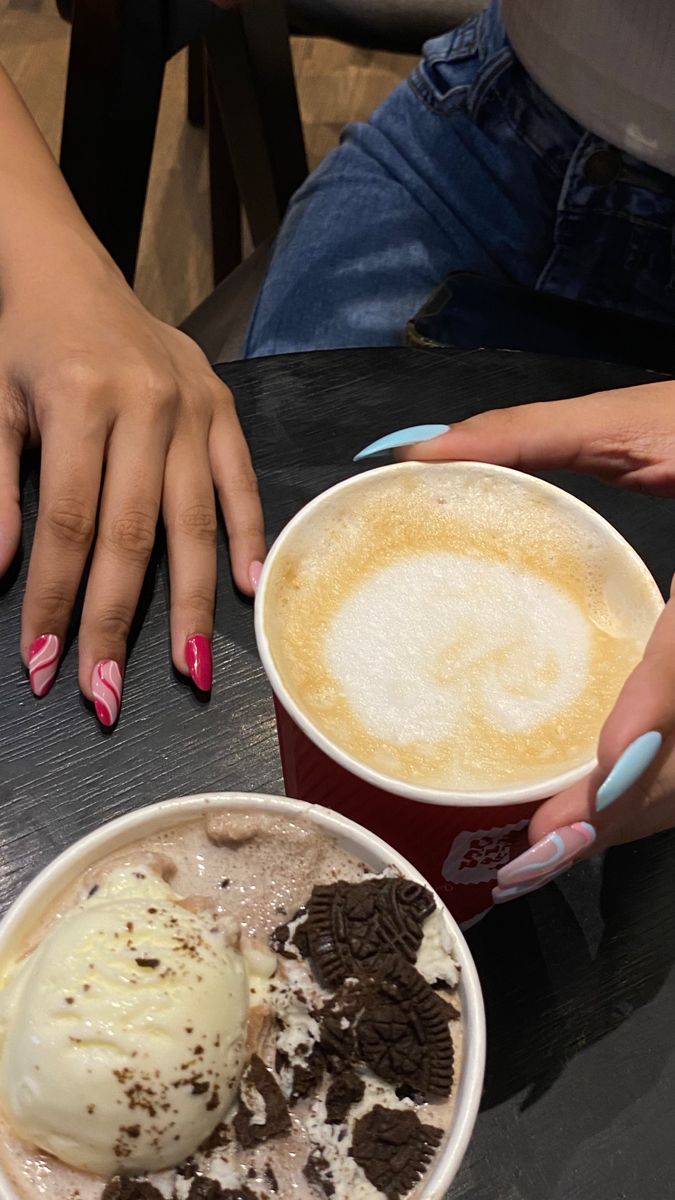 two people sitting at a table with ice cream and cookies