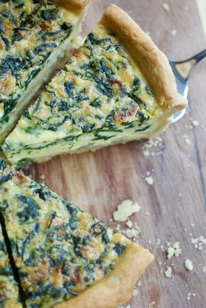 spinach and cheese quiche on a wooden cutting board