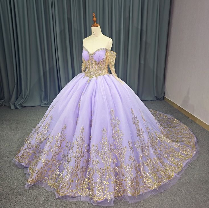 Experience ultimate luxury with our exquisite Princess Purple and Gold Quinceañera Ball Gown. This regal dress boasts a sweetheart front bodice and a gold-trimmed illusion corset, adorned with off-the-shoulder beaded gold long sleeves. The gathered full skirt is elegantly trimmed in gold and features a train, while the lace-up back allows for a customizable fit. Elevate your event with this exclusive and sophisticated masterpiece. material: organza, glitter tulle, lace type: a line ball gown style: formals color as shown built in bra sweetheart neckline train as shown lace up back Quince Dresses Purple And Gold, Purple And Gold Dress Gowns, Purple And Gold Wedding Dress, Purple And Gold Quinceanera Dresses, Rapunzel Quinceanera, Tangled Quince, Ballroom Extravaganza, Regal Dress, Tangled Wedding