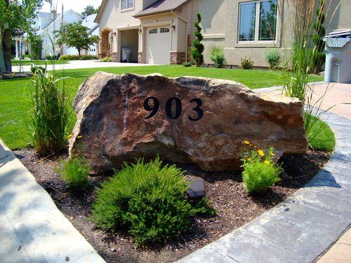 a large rock with the number 903 on it in front of some bushes and trees