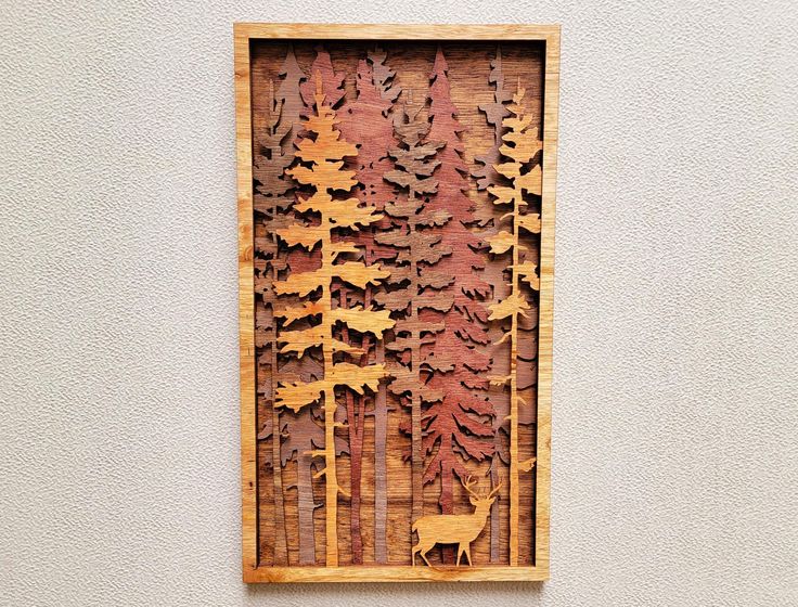 a wooden cut out of trees with a deer in the woods on it's side