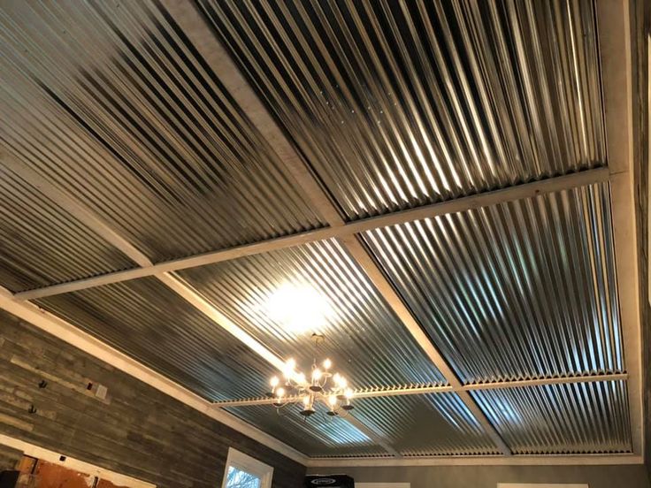 a room with a ceiling made out of metal sheets and lights hanging from the ceiling