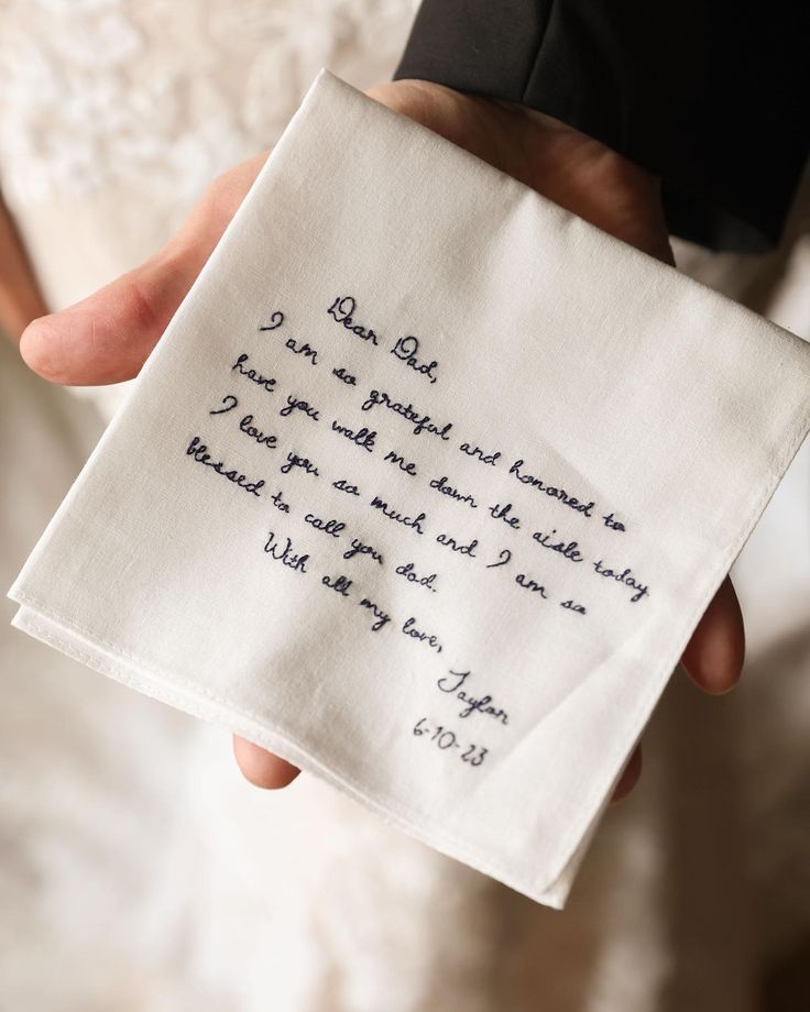 a person holding a piece of cloth with writing on it in their left hand while wearing a tuxedo