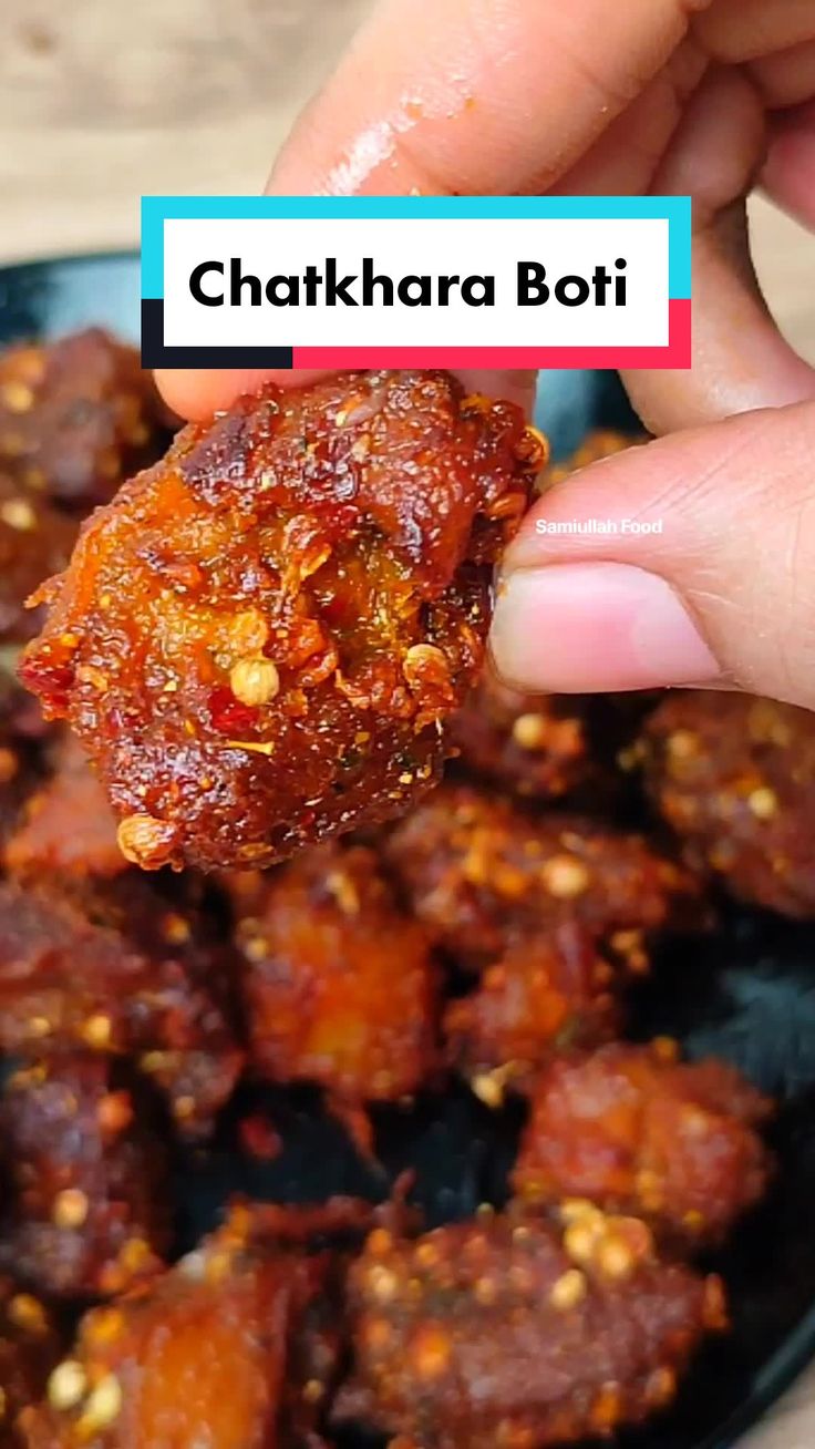 a person dipping some food into a black bowl with other foods in the back ground