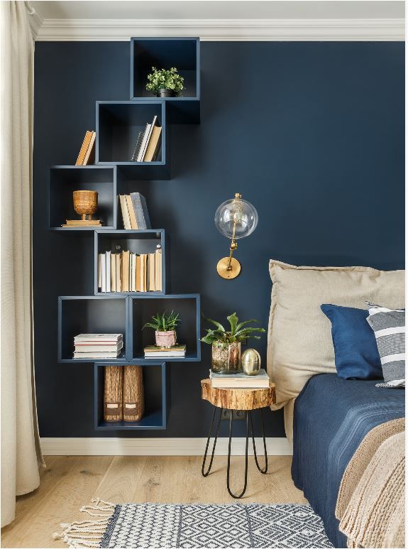 a bedroom with blue walls and bookshelves on the wall