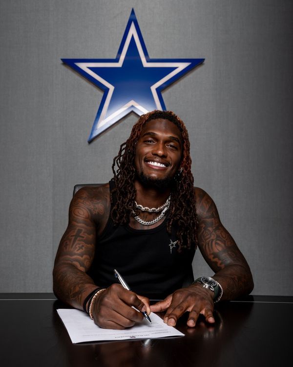 a man sitting at a table with a pen in his hand and a star on the wall behind him