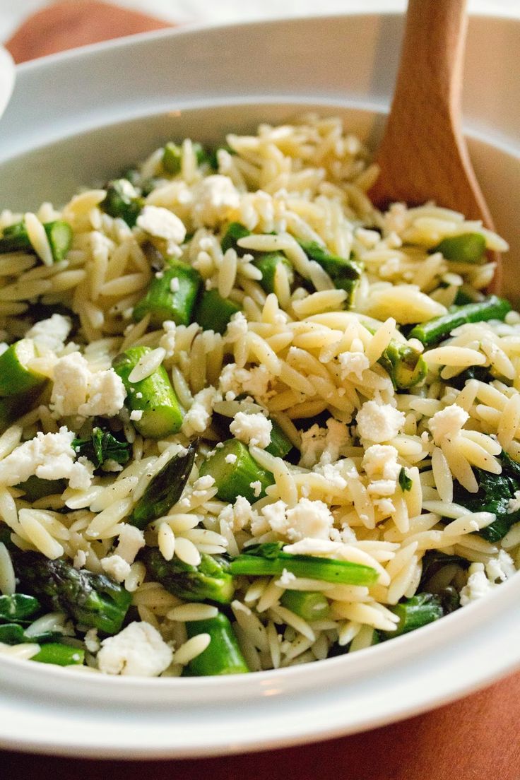 a white bowl filled with pasta and asparagus