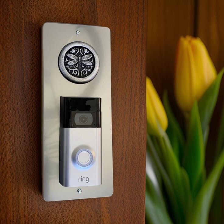 a close up of a button on a door handle with flowers in the back ground