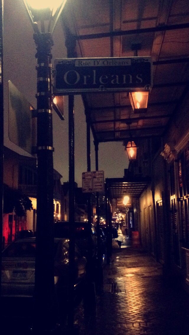 a street sign that is on the side of a pole in the dark with lights