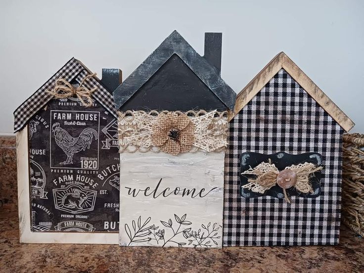 three small wooden houses sitting on top of a counter next to each other with the word welcome written in front of them