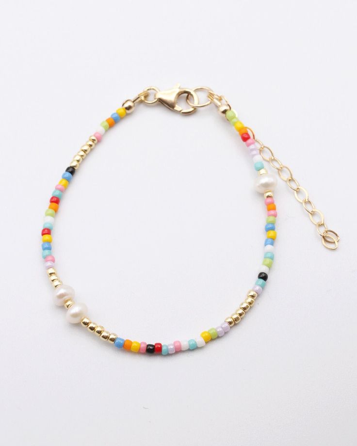 "With the multicolor beads of the Marthe Bracelet pairing with so many outfit colors, you may just find yourself wearing this for most of the spring and summer!  We especially love the special freshwater pearls mixed in with the seed beads here and there for a little something extra.  Love this look?  Add the Marthe Necklace for a complete look. About the Artisan Marie Marthe is a wonderful Haitian artisan that has been a part of our team for years!  She is a talented seamstress and dedicated team member.  We are thrilled she is part of the Vi Bella artisan family. Details 6\" seed bead bracelet freshwater pearls 2\" gold plated extender chain Handmade by Vi Bella Artisans in Haiti" Colorful Beaded Bracelets For Everyday Summer Wear, Adjustable Multicolor Pearl Bracelet With Colorful Beads, Multicolor Beaded Bracelets For Everyday Summer Wear, Everyday Pearl Bracelet With Colorful Round Beads, Multicolor Pearl Bracelet With Colorful Beads, Spring Gold Beaded Bracelets With Colorful Beads, Multicolor Beaded Bracelets With Pearl Charm As Gift, Multicolor Pearl Bracelet With Spacer Beads As A Gift, Multicolor Pearl Bracelet With Spacer Beads