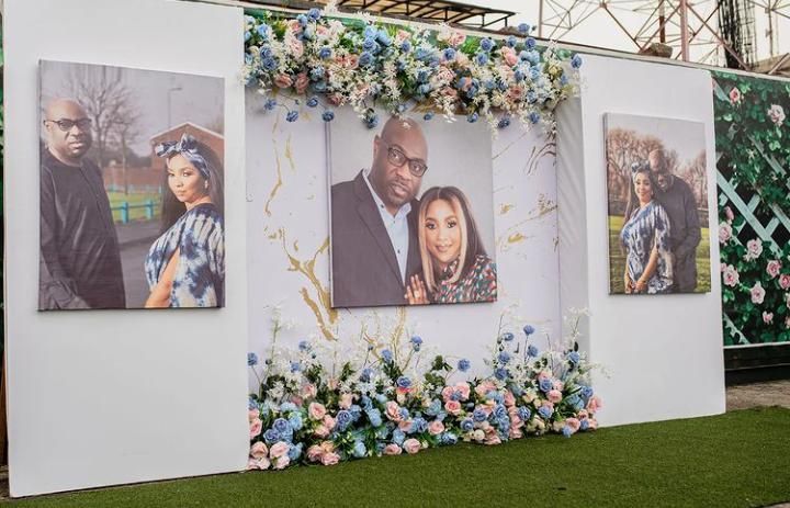 a large white wall with three pictures on it and flowers around the edges, in front of a building