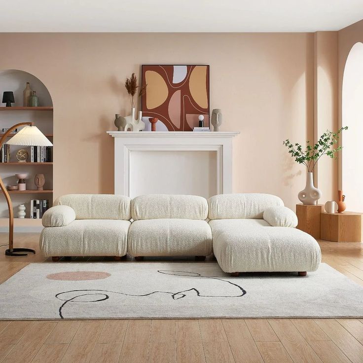 a white couch sitting on top of a hard wood floor next to a fire place