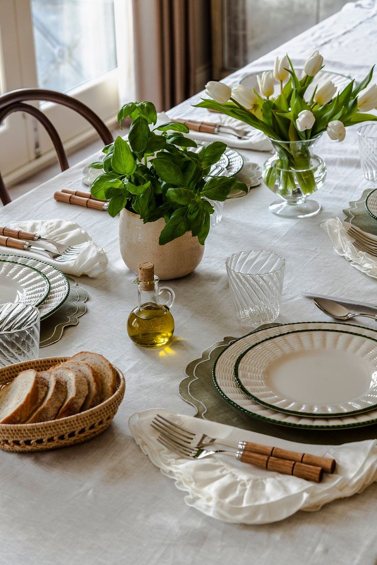 the table is set with plates, silverware and flowers in vases on it