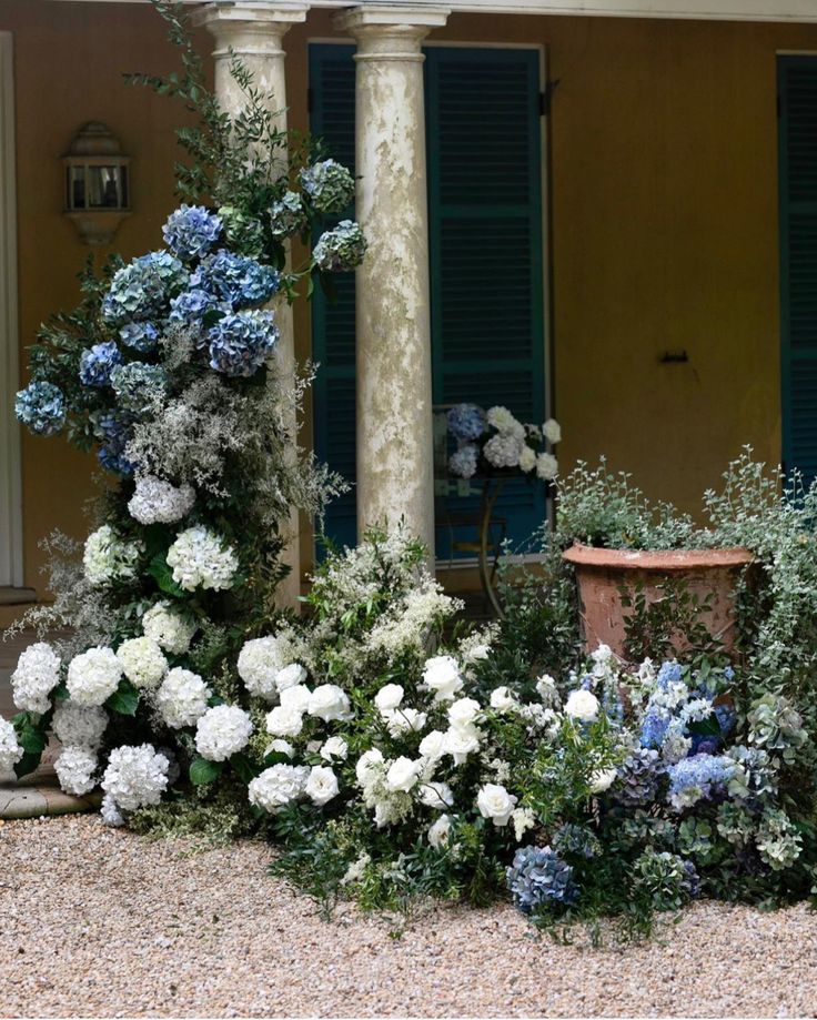 blue and white flowers are in front of a house