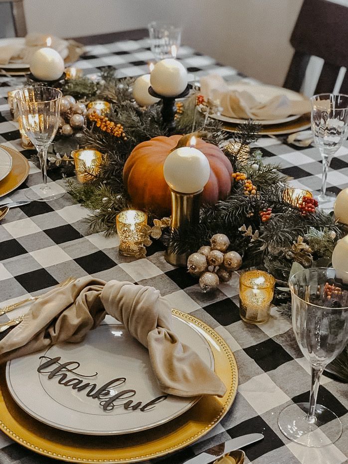 a black and white checkered table cloth with candles, plates and napkins on it