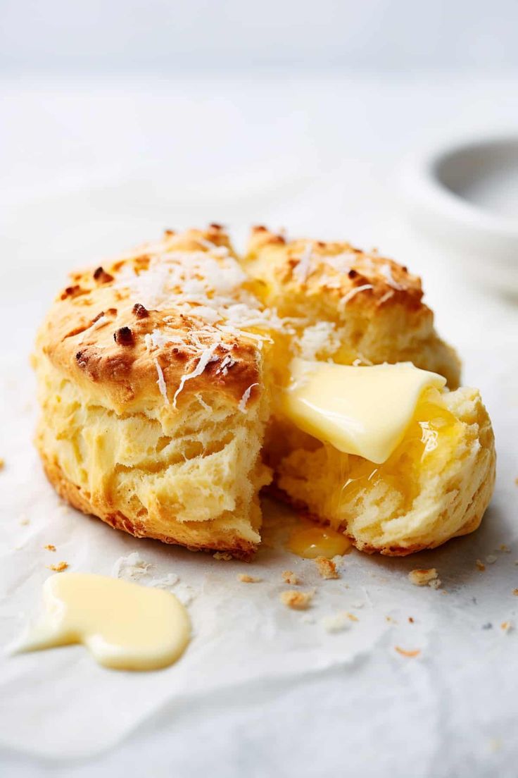 a biscuit with butter on it is sitting next to a small bowl