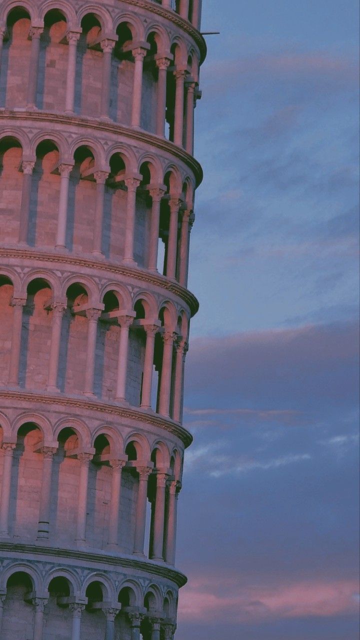 the leaning tower is very tall and has many arches on it's sides at dusk