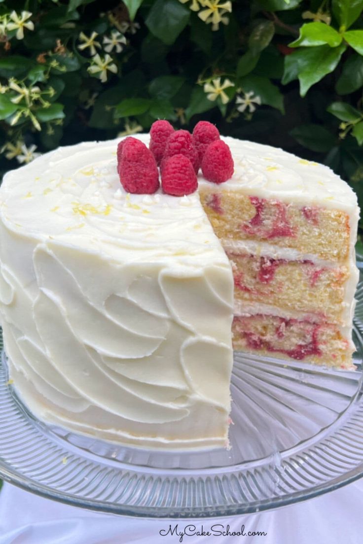 a cake with white frosting and raspberries on top