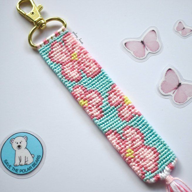 a beaded keychain with pink and blue flowers on it next to some butterflies