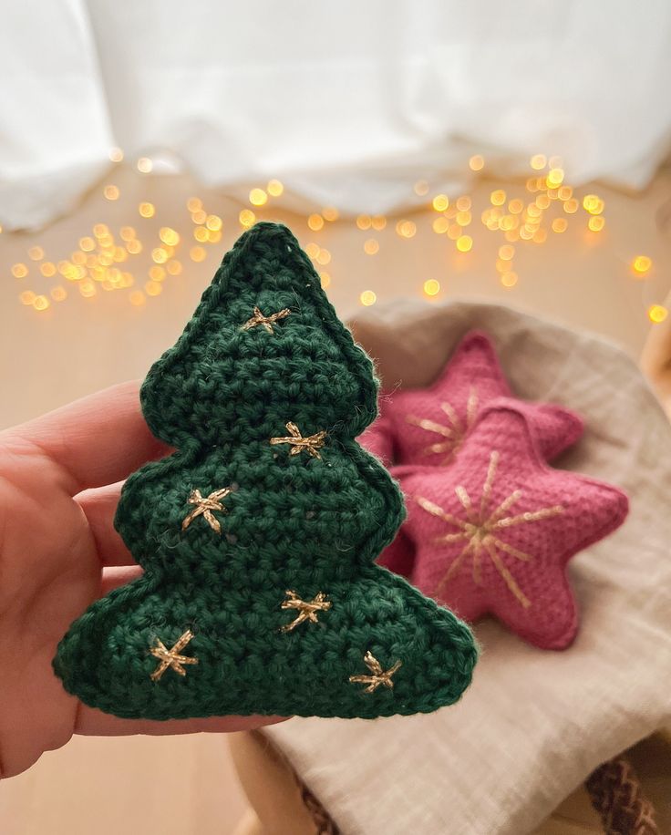 two crocheted christmas trees sitting next to each other on top of a table