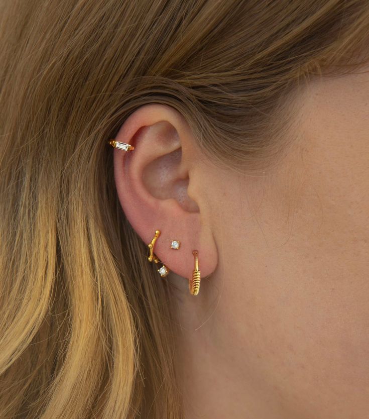 a close up of a person wearing some kind of gold earring on their left ear