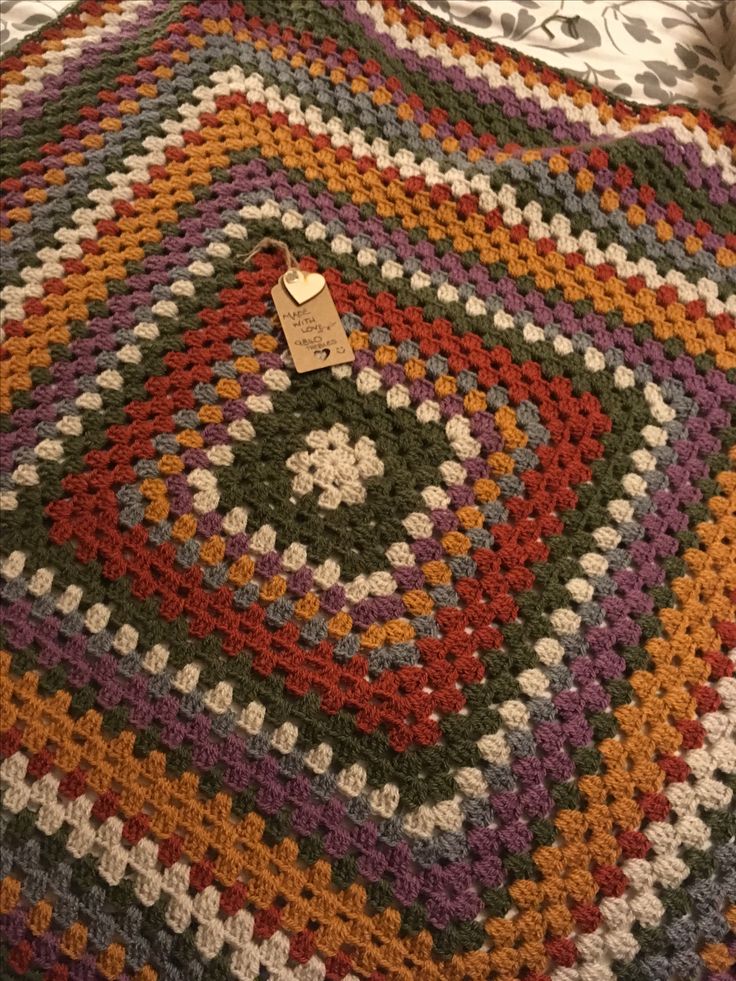 a crocheted blanket with a button on it sitting on top of a bed