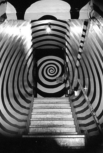 an escalator leading up to a spirally painted wall