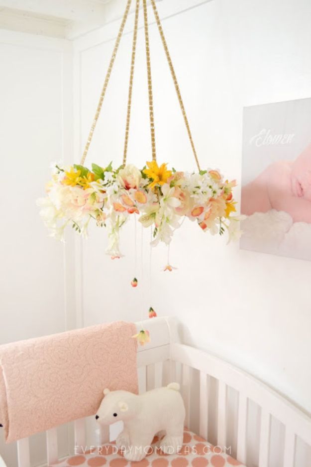 a baby crib with flowers hanging from it's ceiling and a stuffed animal on the bed