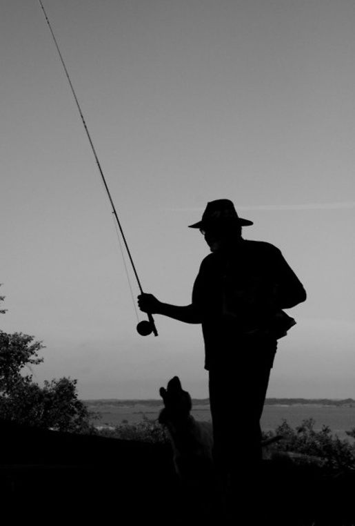 a man standing next to a dog while holding a fishing pole