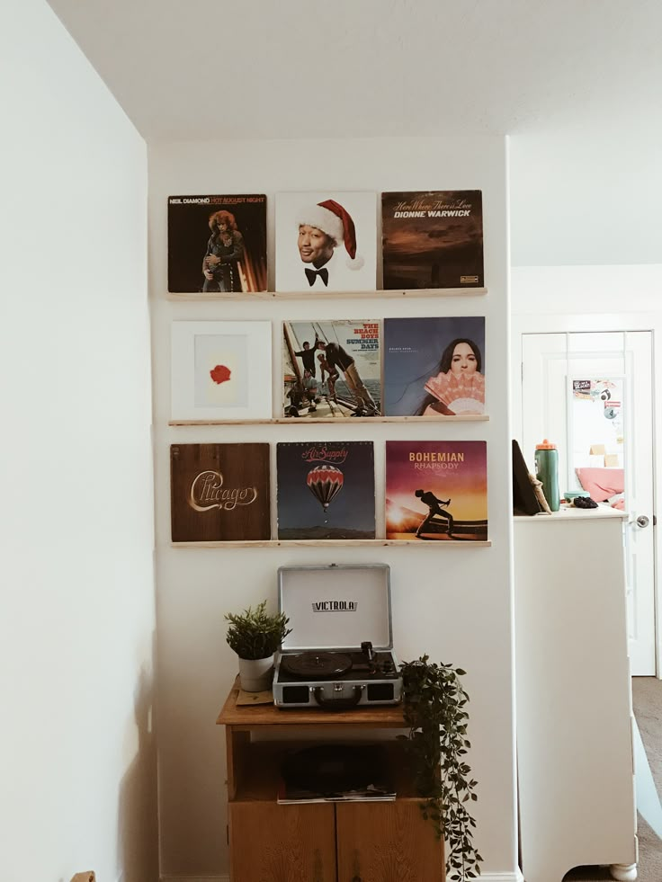 a laptop computer sitting on top of a wooden table in front of a wall with pictures