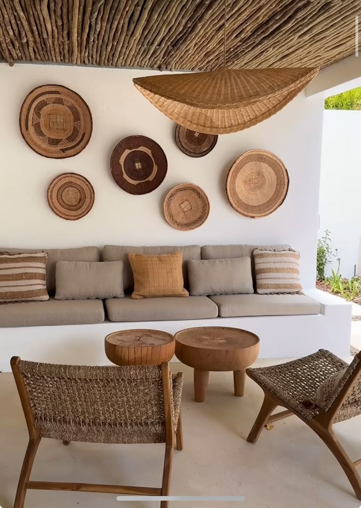 a living room filled with lots of furniture and wall hangings above the couches