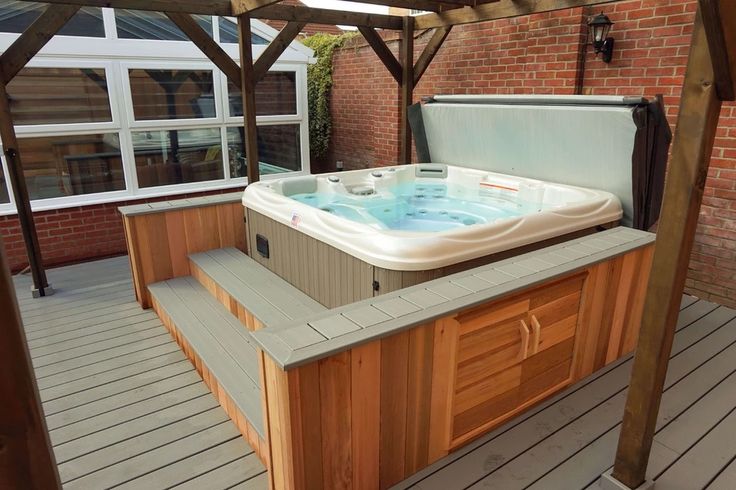 a hot tub sitting on top of a wooden floor next to a brick building with windows