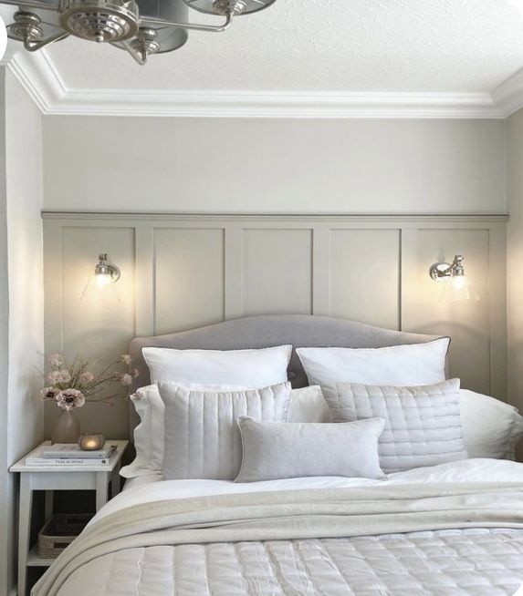 a bed with white linens and pillows in a small room next to a wall