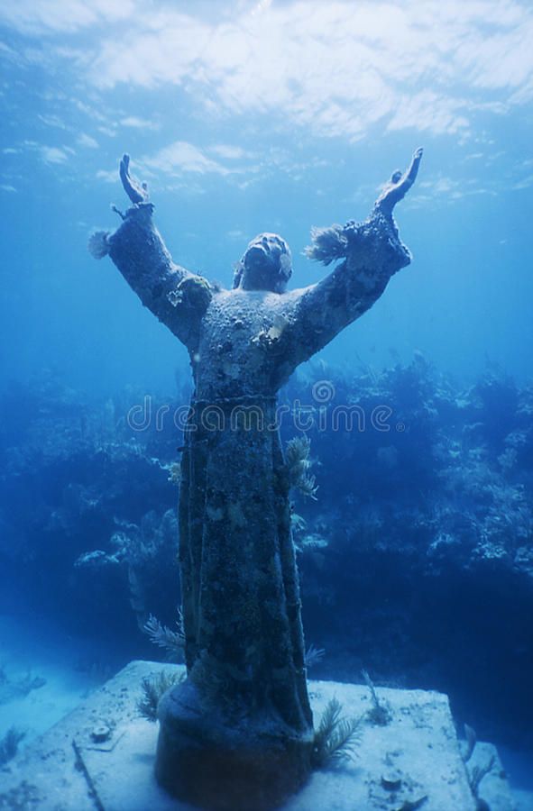 the statue is under water and has its arms up in the air with his hands outstretched