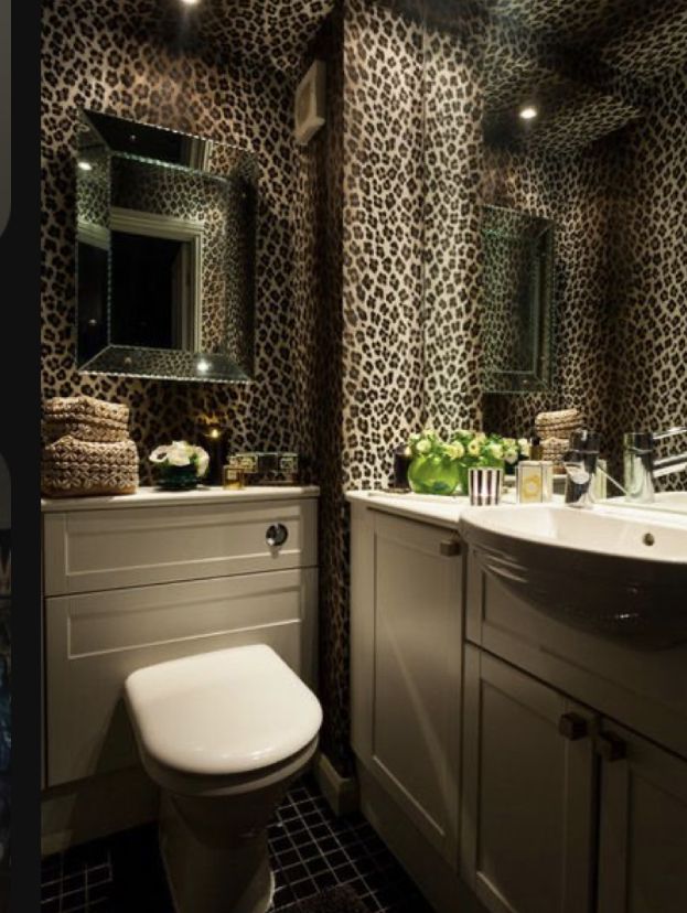 a bathroom with leopard print wallpaper and white fixtures, including a toilet and sink