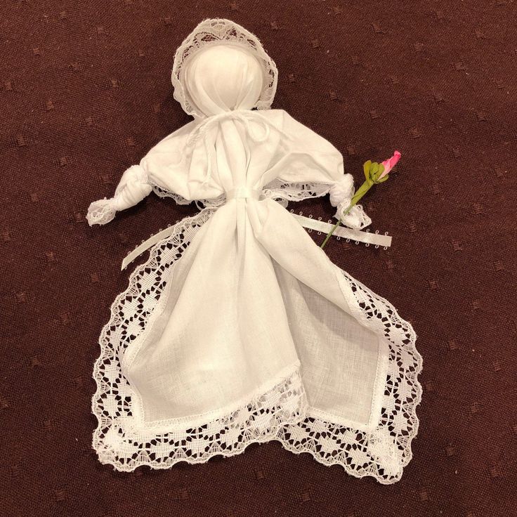 a white doll is laying on the ground with a rose in it's hand