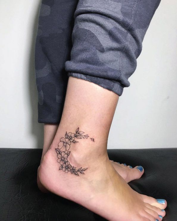 a woman's foot with a small flower tattoo on her left side calfocks