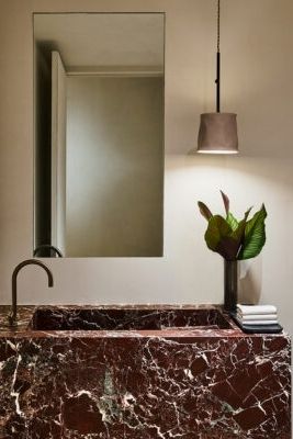 a bathroom sink with a marble counter top next to a mirror and light above it