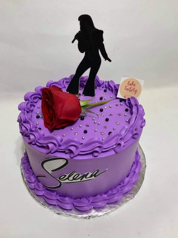 a purple cake with a figure on top and a red rose in the middle that says sequin