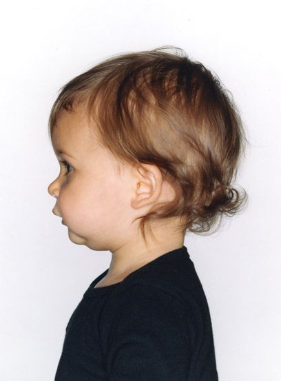 a small child with brown hair wearing a black shirt and looking off into the distance