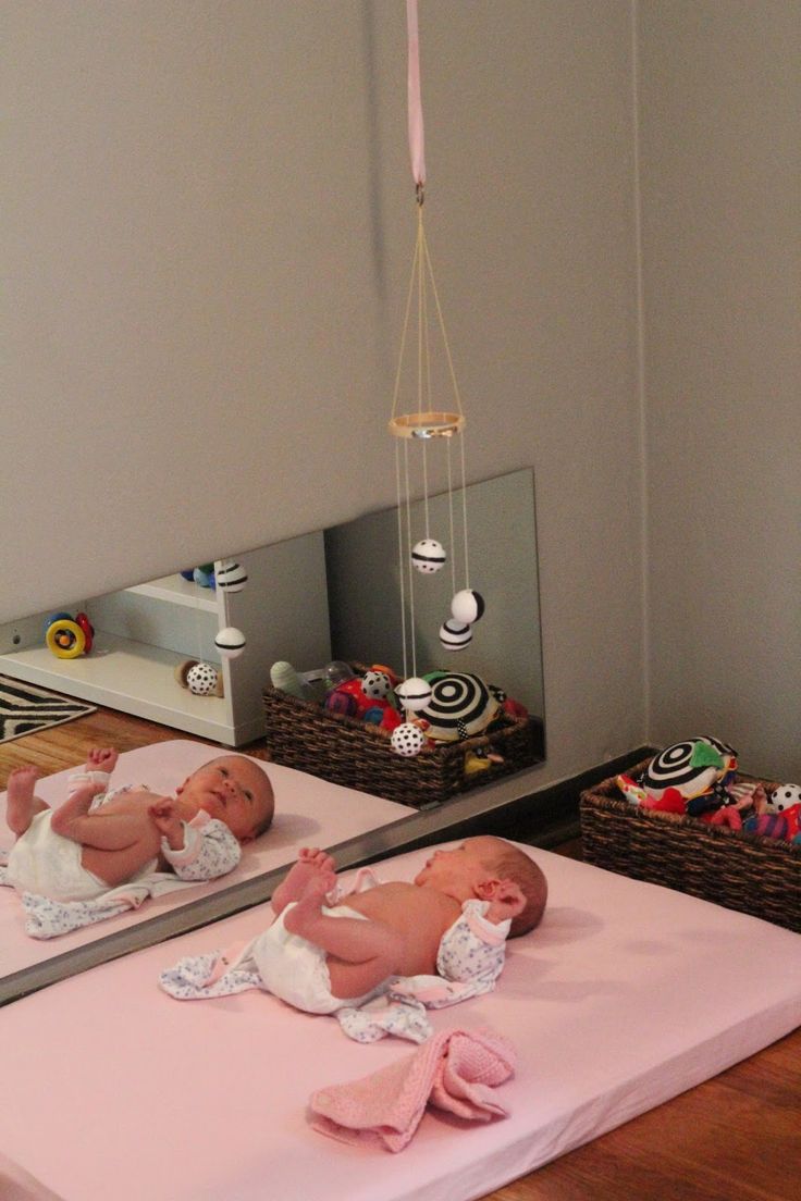 two baby dolls are laying on their stomachs in front of a mirror that is hanging from the ceiling