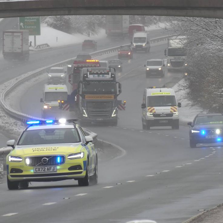 police cars and ambulances driving on a snowy road