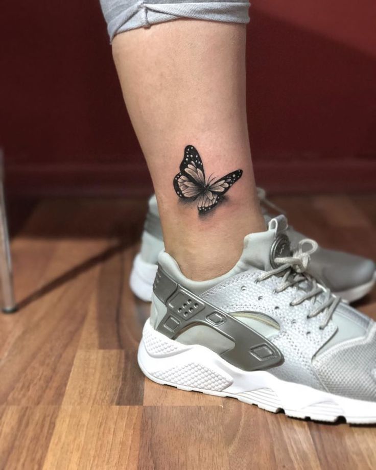 a woman's foot with a butterfly tattoo on her left ankle and right leg