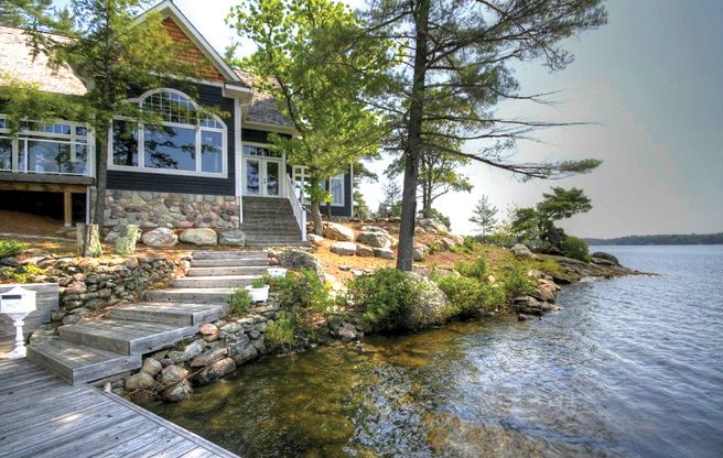 a house on the shore with stairs leading up to it's water front porch